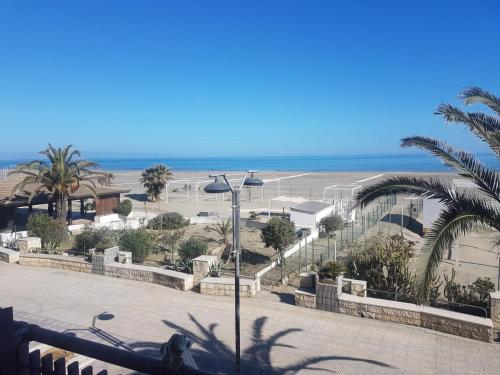 vistas a una playa con palmeras y luz de la calle en La Vela Apulia Seaside Residence, en Margherita di Savoia