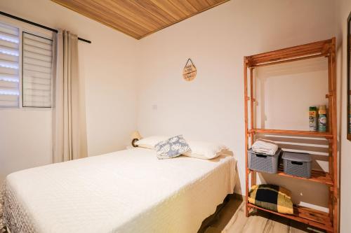 a bedroom with a white bed and a shelf at Terra Sertaneja - Chalé Evidências II in Piedade