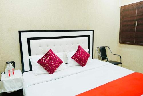 - une chambre avec un lit blanc et des oreillers rouges dans l'établissement millenium homestay, à Varanasi