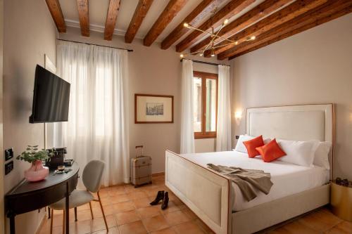 um quarto com uma cama, uma secretária e uma televisão em Daplace - Antica Casa Coppo em Veneza