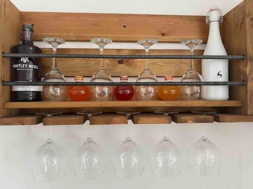 a row of wine glasses and bottles on a shelf at Modern home on the edge of the Cotswolds in Evesham