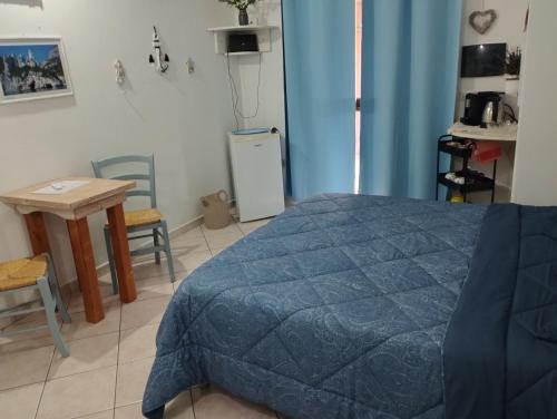a bedroom with a blue bed and a table and chairs at Affittacamere Casa del Sole in Cala Gonone