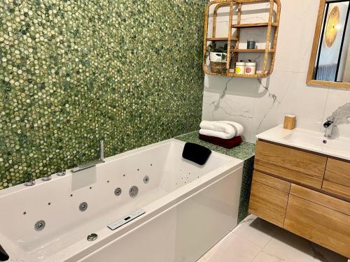 La salle de bains est pourvue d'une baignoire et d'un lavabo. dans l'établissement LuxeZen - SPA, à Villeurbanne