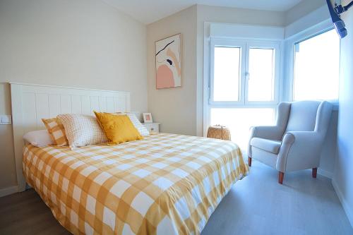 a bedroom with a bed and a blue chair at GALIHOST - Apartamento con vistas al Náutico de San Vicente in O Grove