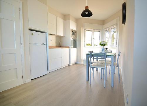 a kitchen with a table and chairs and a refrigerator at GALIHOST - Apartamento con vistas al Náutico de San Vicente in O Grove