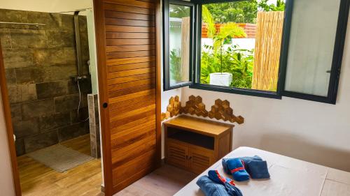 a bathroom with a shower and a bed and a window at Bungalow Vétyver in Saint-Pierre