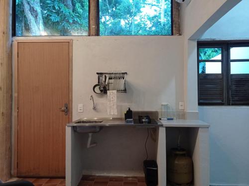 uma cozinha com um balcão com um lavatório e uma janela em Pousada Sobre A Rocha em Praia de Araçatiba