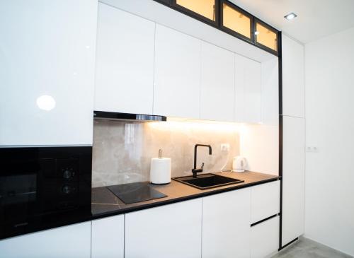 a kitchen with white cabinets and a sink at Apartmani Mila in Laktaši
