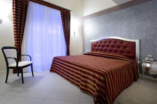 a bedroom with a bed and a chair and a window at Monastero Resort & Spa - Garda Lake Collection in Soiano del Lago