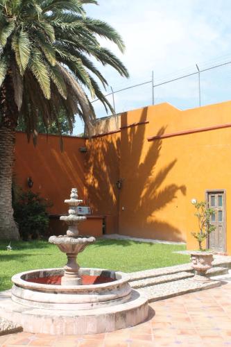 une fontaine en face d'un bâtiment avec un palmier dans l'établissement Casa Rosa Amelia, à Guadalajara