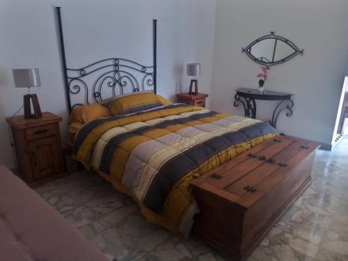 Casa Rosa Amelia في غواذالاخارا: غرفة نوم مع سرير وصدر خشبي في النهاية