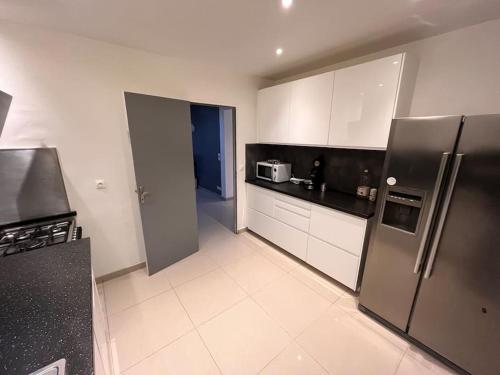 une cuisine avec des armoires blanches et des appareils en acier inoxydable dans l'établissement Maison dans Résidence pavillonnaire paisible, à Cannes-Écluse