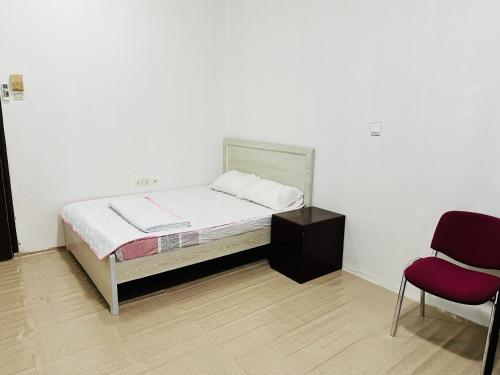 a small bedroom with a bed and a chair at Big bedroom in apartment sharing washroom in Sharjah