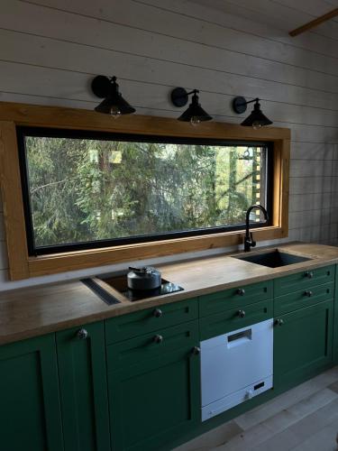 a kitchen with a sink and a window above a counter at The Sunset Cabin будиночок з Чаном in Zhuraky