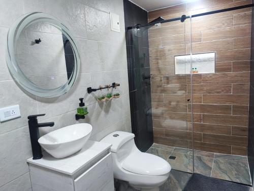 y baño con aseo, lavabo y ducha. en Hotel a resting place 1 AEROPUERTO en Bogotá