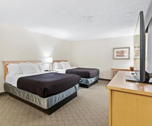 a hotel room with two beds and a flat screen tv at Travelodge Hotel by Wyndham Saskatoon in Saskatoon