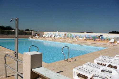 - une grande piscine bordée de chaises longues blanches dans l'établissement Mobile home à 200m de la mer dans camping familial avec piscine, jeux et activités, à Pornic