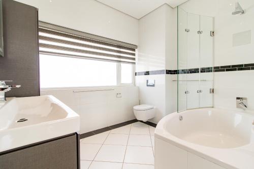 a bathroom with a sink and a tub and a toilet at Eye Of Africa Luxury Golf Suite in Eikenhof