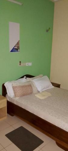 1 dormitorio con 2 camas y pared verde en Guest bidossessi, en Abomey-Calavi