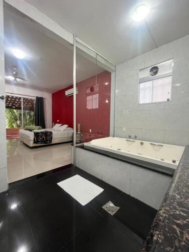 a large bathroom with a tub and a bed at Pousada Cantim de BH in Venda Nova