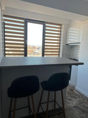 a kitchen with two blue bar stools at a counter at Apartament bloc nou - self check in - free parking in Craiova