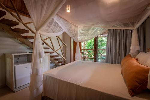 a bedroom with a large bed with curtains at Pousada Cajueiro Trancoso in Trancoso