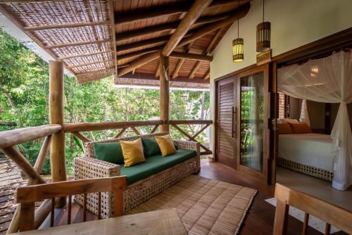 a room with a couch and a bed on a balcony at Pousada Cajueiro Trancoso in Trancoso