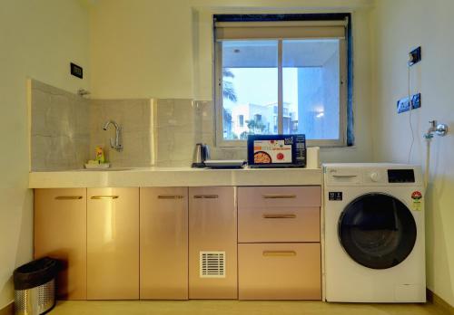 a kitchen with a washing machine and a window at Home2 Studio Apartments in Mumbai