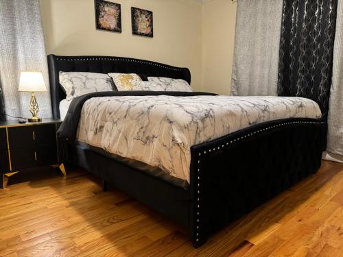 1 cama negra grande en un dormitorio con suelo de madera en Affordable Luxury Home Near NYC & EWR, en Newark