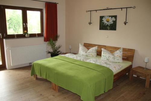 ein Schlafzimmer mit einem Bett, auf dem eine grüne Decke liegt in der Unterkunft Vitaleum in Krölpa