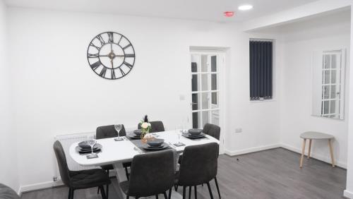 a dining room with a table and a clock on the wall at ETIHCITY - 3 Bedroom Semi - Free Parking near Etihad Stadium, Tourist attractions, Manchester City Centre, Transport and Motorway Links next to McDonald's - Sky n Netflix in Manchester