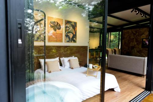 um quarto de vidro com uma cama e uma banheira em CHALÉ NAMATA 201 em São Roque