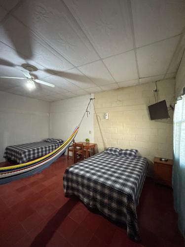 a room with two beds and a hammock in it at Hotel y Restaurante El Cafetalito in Conchagua