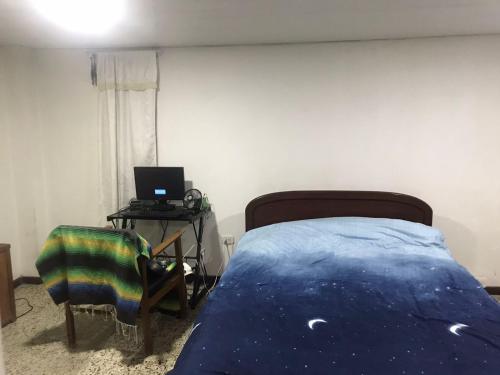 a bedroom with a bed and a desk with a laptop at CASA EN EL QUINDÍO in Armenia
