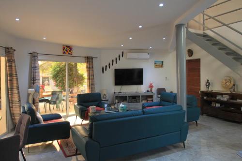 a living room with blue couches and a tv at Amour Sénégal in Ngaparou