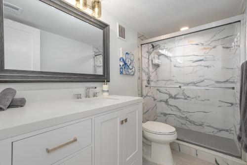a bathroom with a toilet and a sink and a mirror at Canaveral Towers Resort-Beach, Surf, Rocket Launches in Cape Canaveral