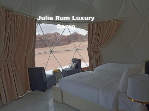 a bedroom with a bed and two chairs and a window at Julia Rum Luxury Camp in Wadi Rum
