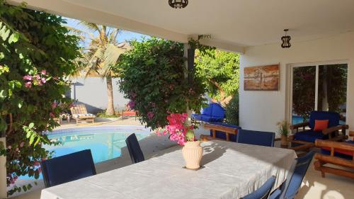 a dining room with a table and a swimming pool at Amour Sénégal in Ngaparou