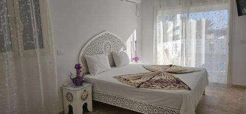 a white bedroom with a bed with a large window at Villa La Palmeraie d'Arkou, grande piscine in Arkou