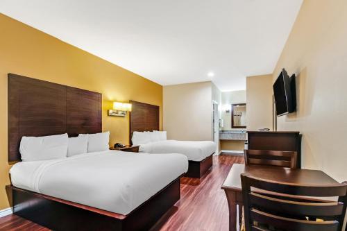 ein Hotelzimmer mit 2 Betten und einem Schreibtisch in der Unterkunft Americas Best Value Inn - FM 529 in Houston