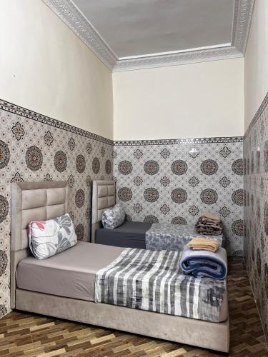 Dar Lala Haniya في الرباط: غرفة نوم بسرير في غرفة مع ورق جدران