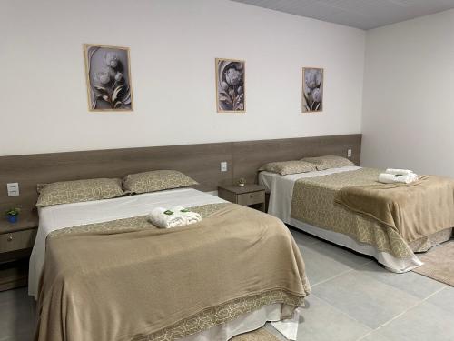 1 dormitorio con 2 camas y toallas. en POUSADA ACONCHEGO MT en Chapada dos Guimarães