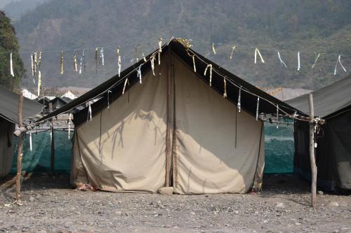 a tent with clothes lines hanging from it next to the water at Wild Leaf Camps in Rishīkesh
