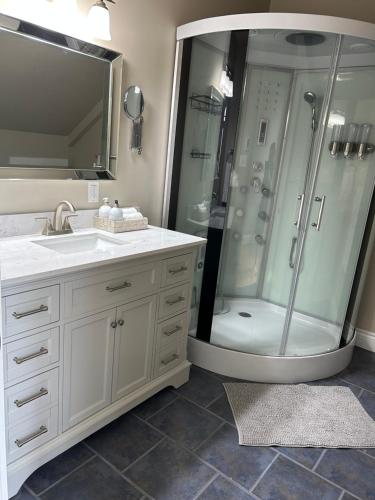 a bathroom with a shower and a white sink at Tides Inn Guest Suites in Halls Harbour