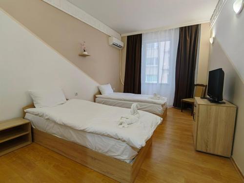 a hotel room with two beds and a tv at Хотел Приятели in Vratsa