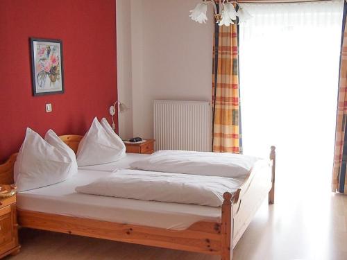 a bedroom with a bed with white sheets and a window at Pension Kreuzberghof in Großklein