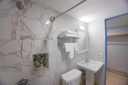 Baño blanco con lavabo y aseo en Aladdin Motel By OYO Merritt Island, en Merritt Island