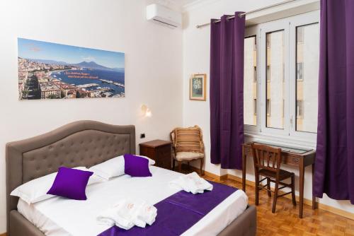 a bedroom with a bed with purple curtains and a desk at Suite Cervantes in Naples