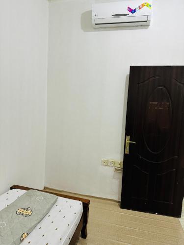 Habitación con cama junto a una puerta negra en Room for single person, en Sharjah