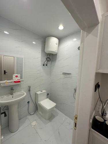 a white bathroom with a toilet and a sink at استديو فاخر بمنطقة مركزية in Riyadh